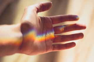 Image of a hand under a streak of rainbow light
